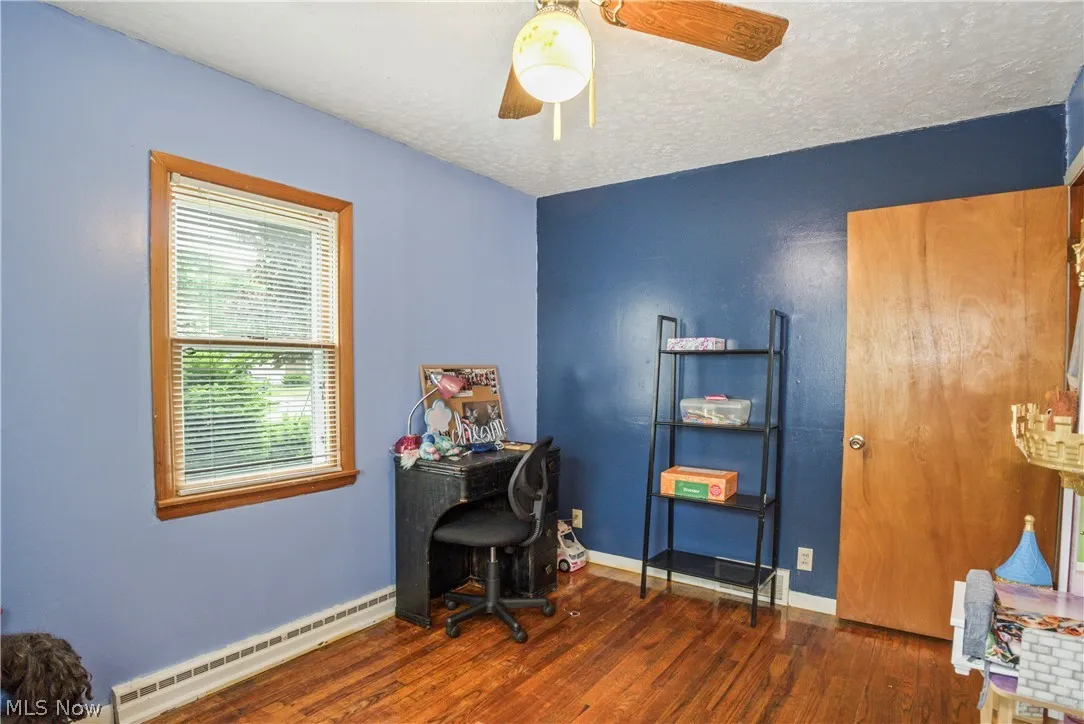 Home office featuring  / wood-style flooring, ceiling fan, a baseboard radiator, and a textured ceiling