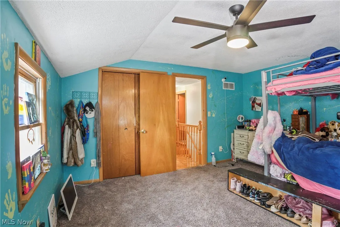 Bedroom featuring lofted ceiling, ceiling fan, a textured ceiling, and carpet flooring