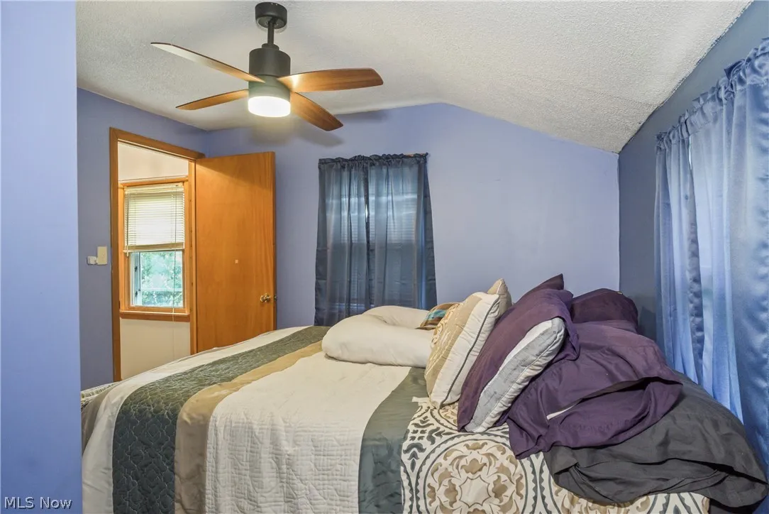 Bedroom featuring lofted ceiling, ceiling fan, and a textured ceiling