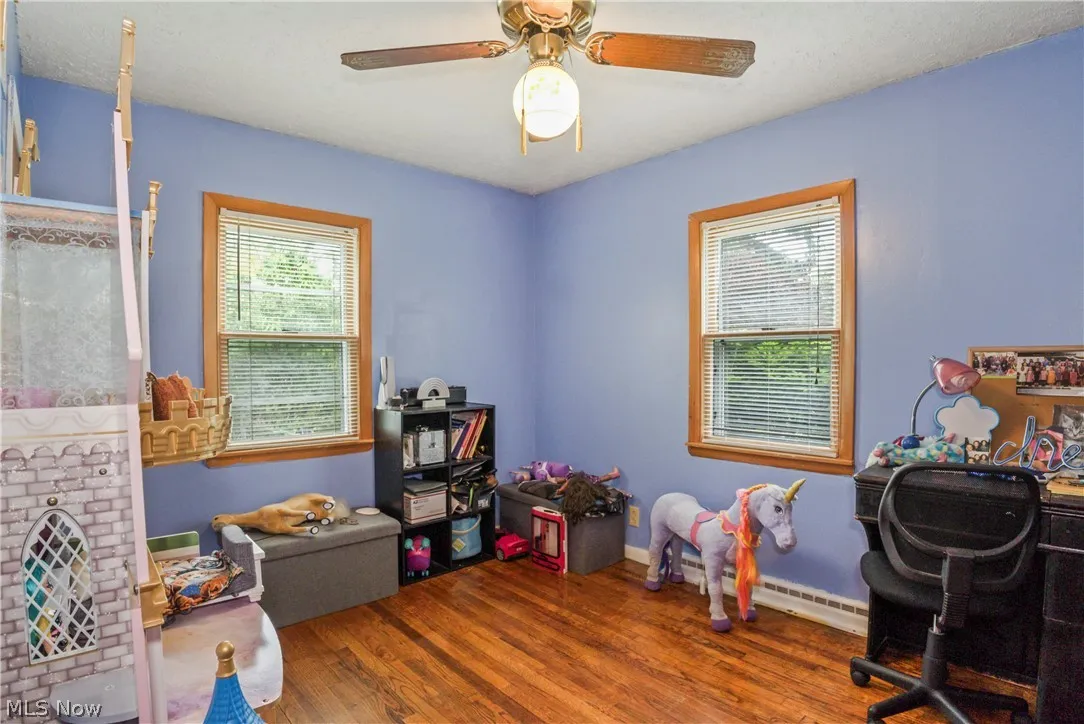 Game room featuring plenty of natural light, wood-type flooring, ceiling fan, and baseboard heating