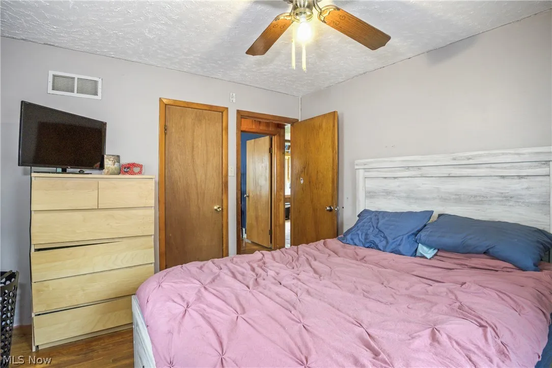 Bedroom featuring dark wood-type flooring, ceiling fan, and a textured ceiling