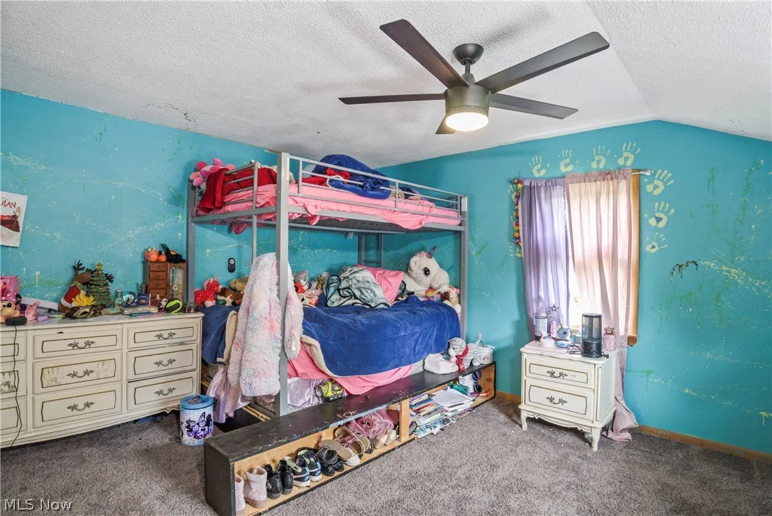 Carpeted bedroom with lofted ceiling, ceiling fan, and a textured ceiling