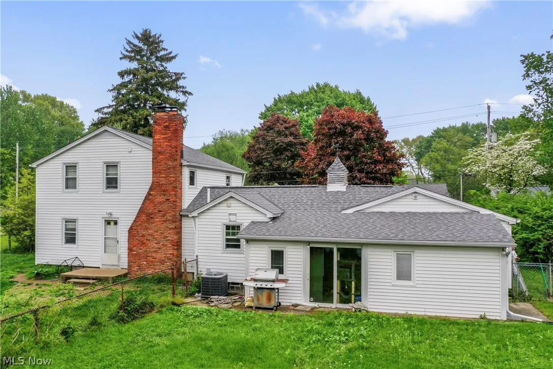 Rear view of house featuring a lawn and central AC unit