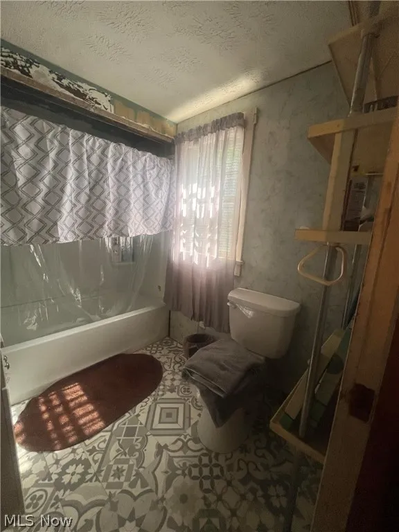 Bathroom featuring a textured ceiling and toilet