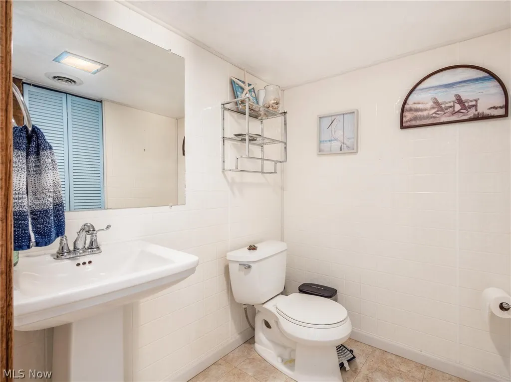Bathroom featuring tile walls, sink, tile flooring, and toilet