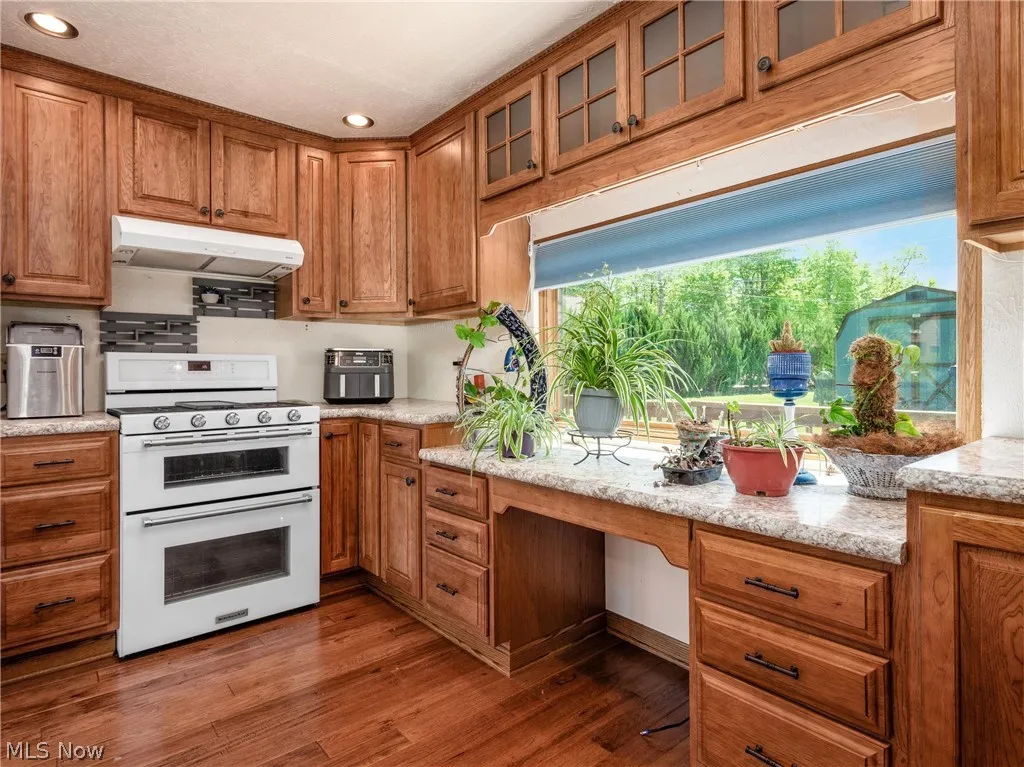 Kitchen with light stone countertops, range with two ovens, and dark hardwood / wood-style floors