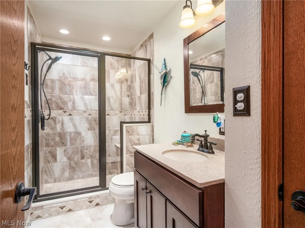 Bathroom with tile floors, an enclosed shower, toilet, and oversized vanity