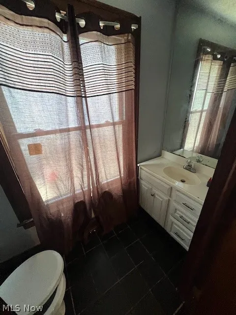 Bathroom featuring tile floors, toilet, and large vanity