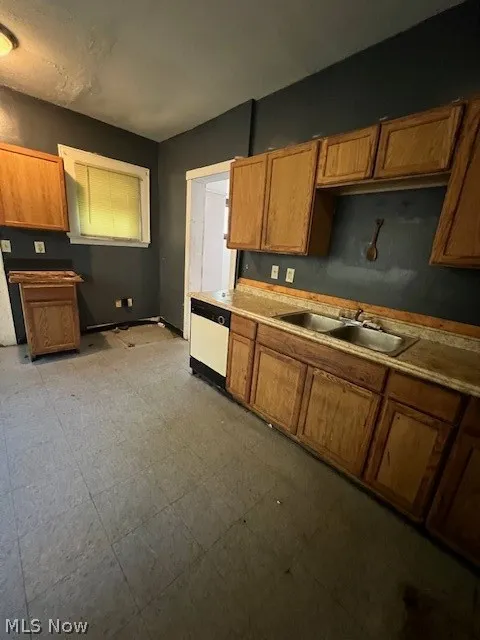 Kitchen with sink, dishwashing machine, and light tile floors