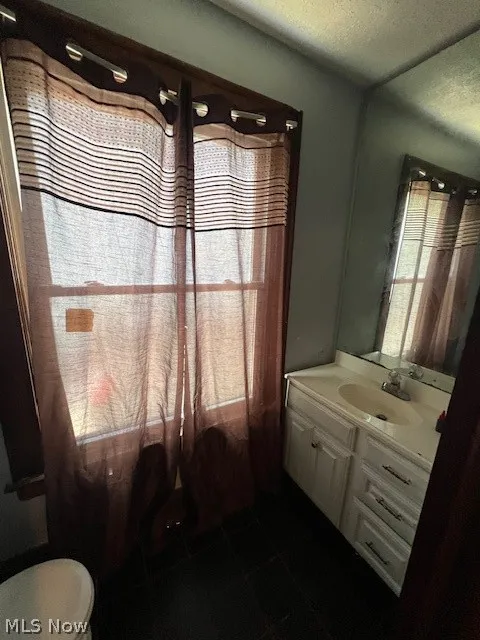 Bathroom featuring tile floors, a textured ceiling, toilet, and vanity