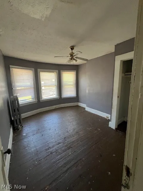 Unfurnished room featuring radiator heating unit, ceiling fan, and hardwood / wood-style floors