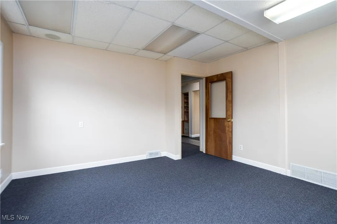 Carpeted empty room featuring a paneled ceiling