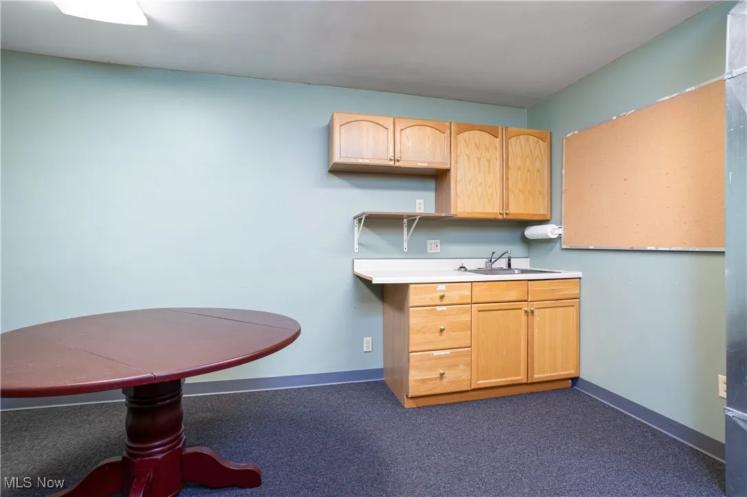Kitchen featuring light brown cabinetry, sink, and dark colored carpet