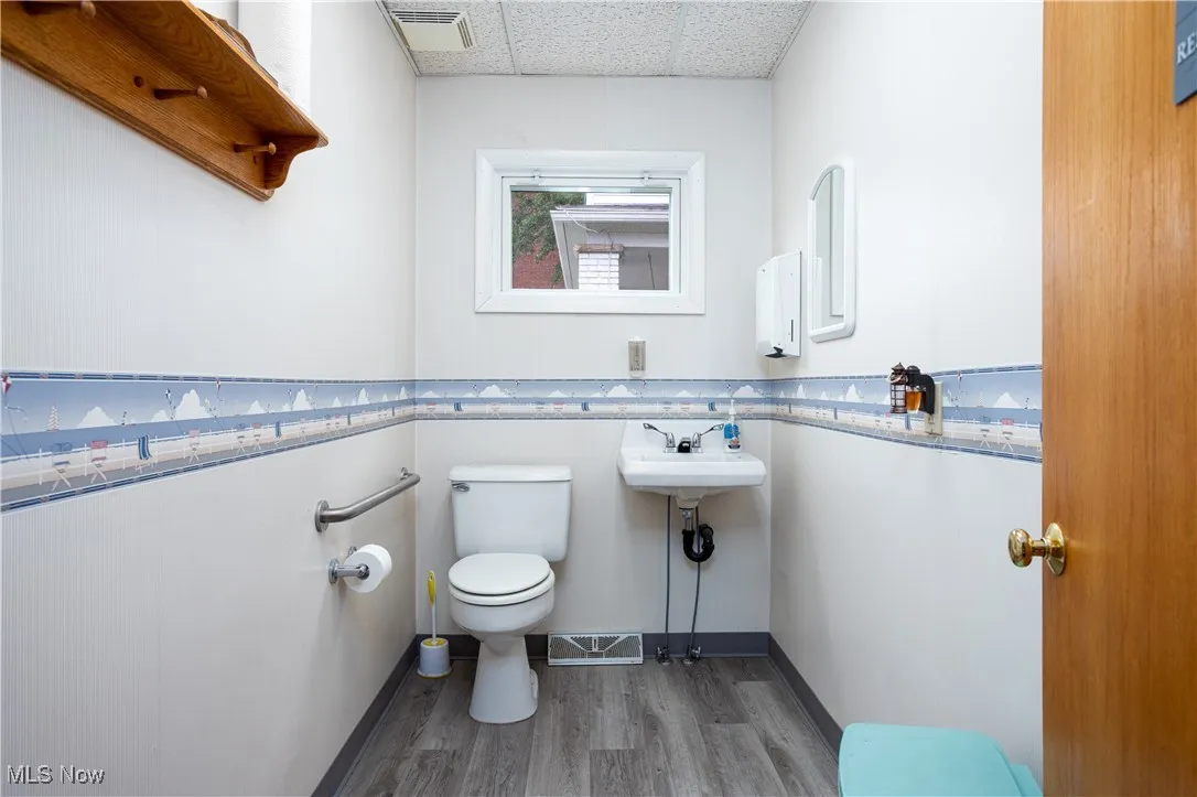 Bathroom featuring a drop ceiling, toilet, and hardwood / wood-style flooring