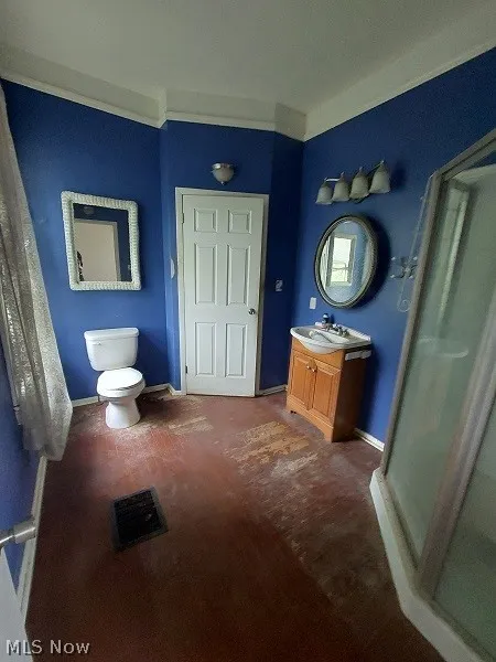 Bathroom featuring walk in shower, ornamental molding, vanity, and toilet