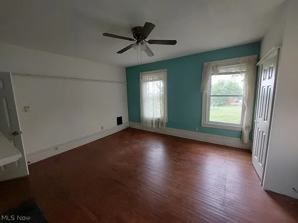 Unfurnished room featuring ceiling fan and dark wood-type flooring