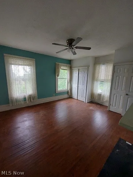 Unfurnished room featuring dark wood-type flooring and ceiling fan