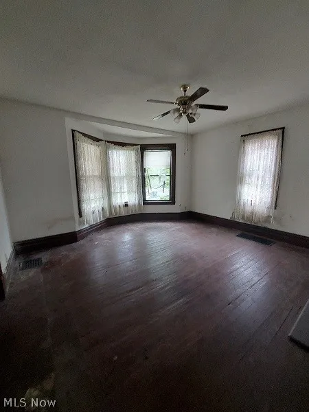 Empty room featuring dark hardwood / wood-style flooring and ceiling fan