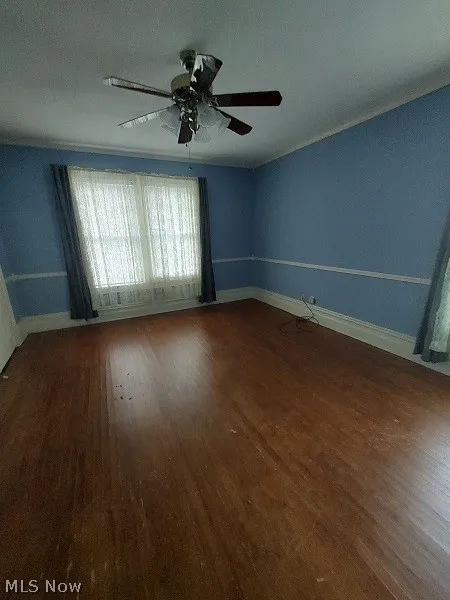 Empty room with dark wood-type flooring and ceiling fan
