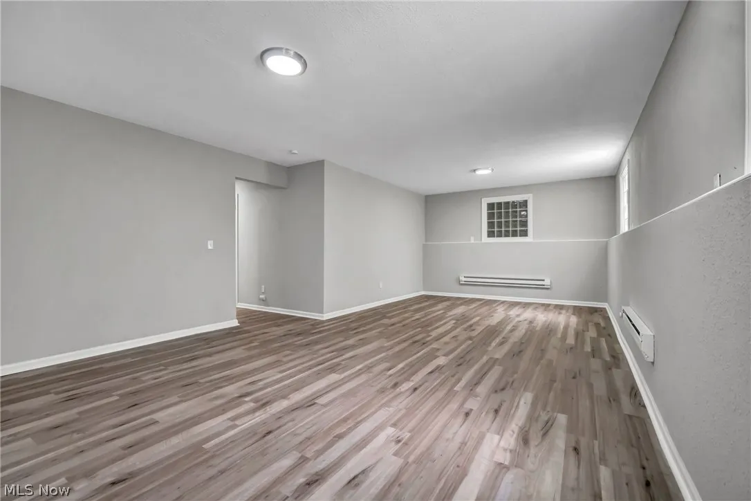 Basement featuring a baseboard radiator and laminate wood-style flooring