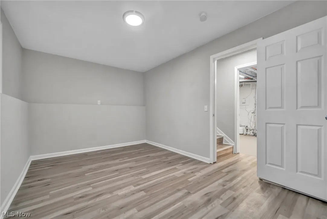 Unfurnished room with light laminate wood-style floors and a baseboard radiator