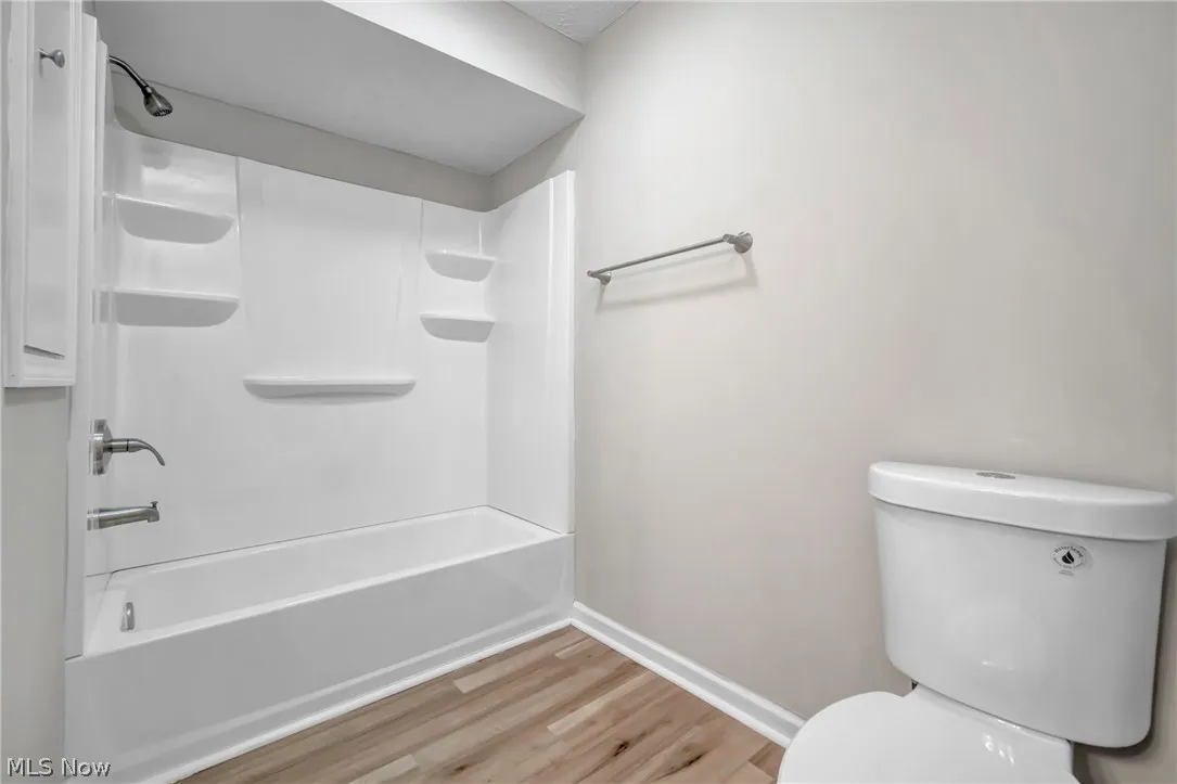 Bathroom featuring wood-style flooring, toilet, and bathing tub / shower combination
