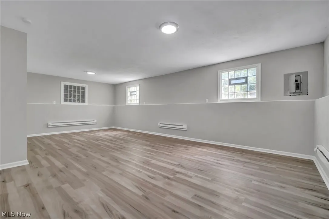 Basement featuring a baseboard radiator and laminate wood-style flooring