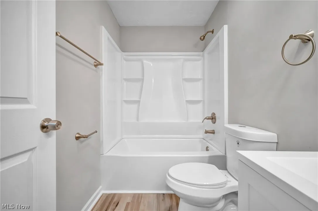 Full bathroom with wood-type flooring, vanity, toilet, and tub / shower combination
