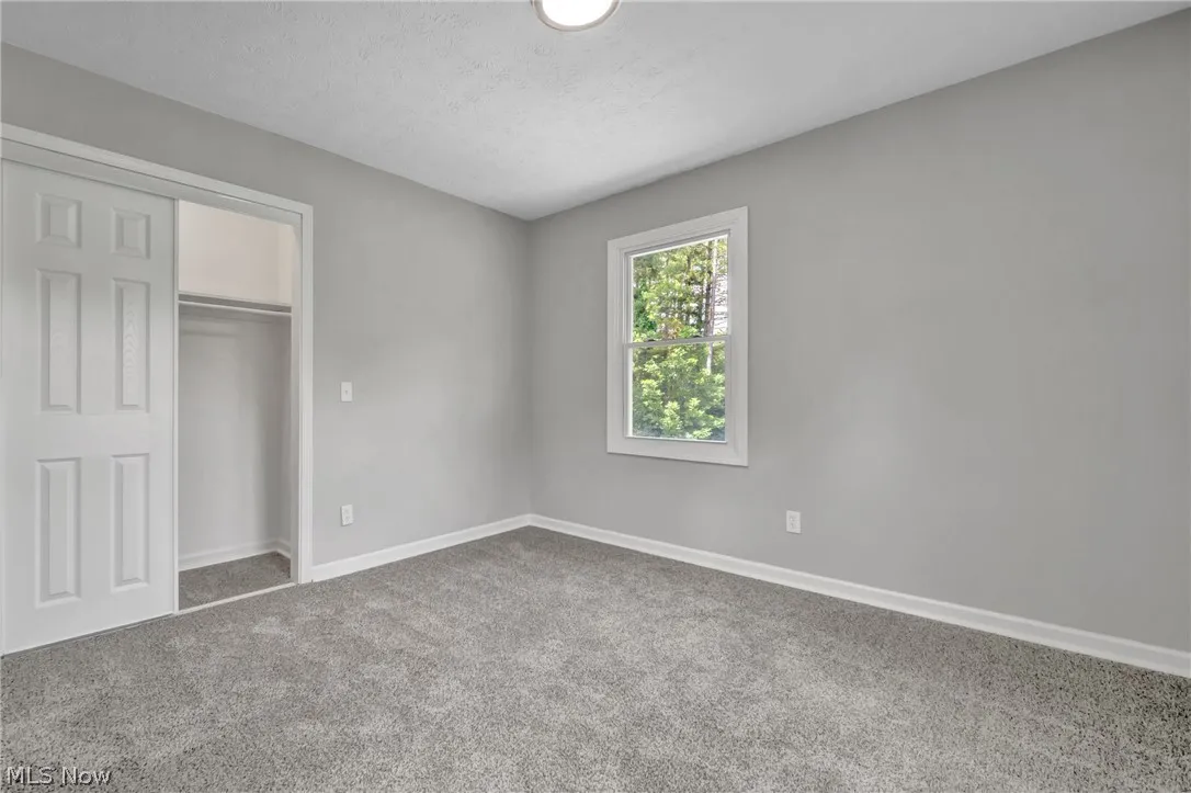 Unfurnished bedroom featuring a textured ceiling, carpet flooring, and a closet