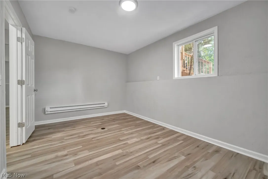 Unfurnished room with light laminate wood-style floors and a baseboard radiator