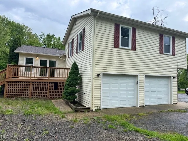 Back of property featuring an attached garage, a deck, and asphalt driveway