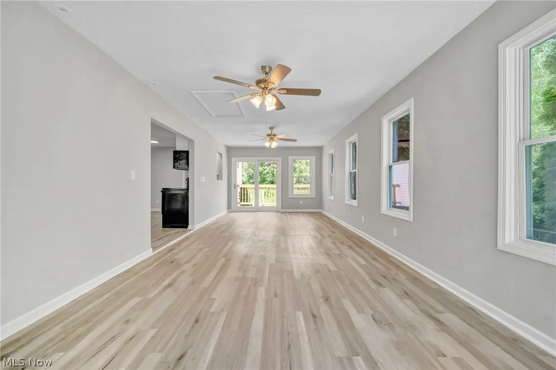 Unfurnished rear sunroom featuring ceiling fan and light wood-type flooring