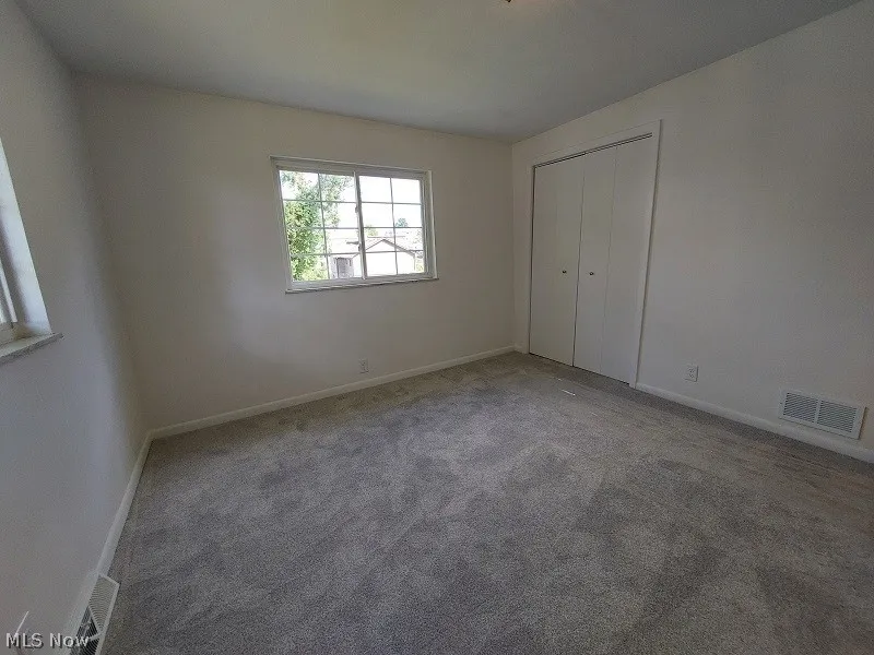 Unfurnished bedroom featuring a closet and dark carpet