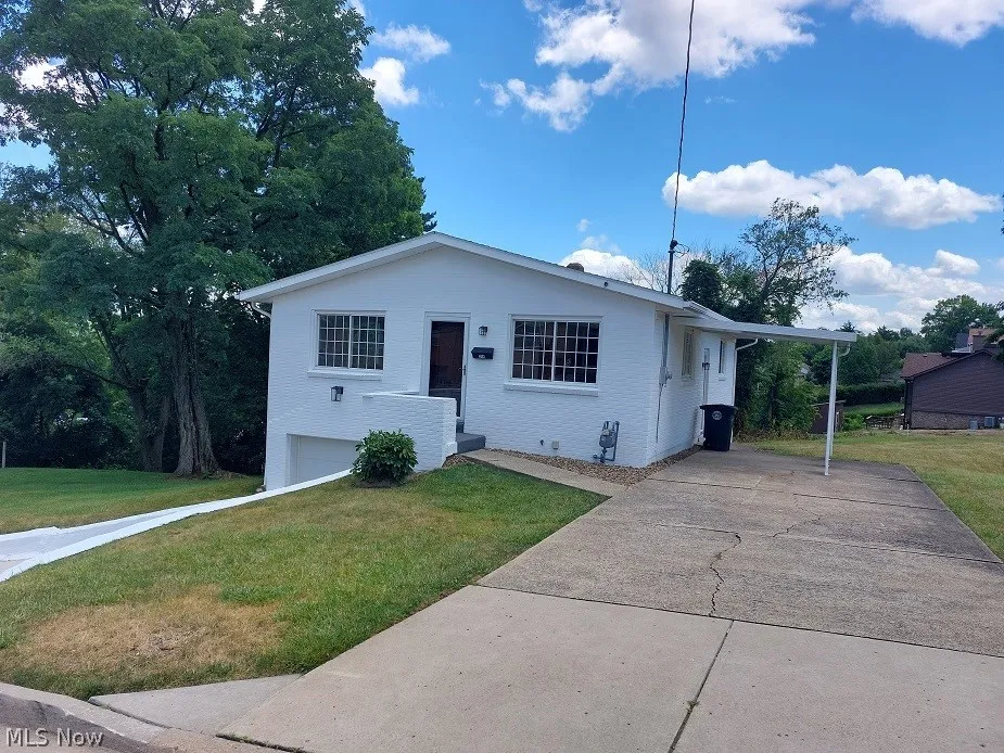 View of front of property with a garage, a front lawn, and a carport