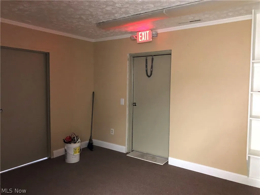  empty room with a textured ceiling and crown molding
