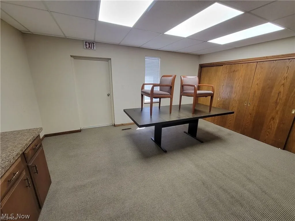 Dining space with carpet floors and a paneled ceiling
