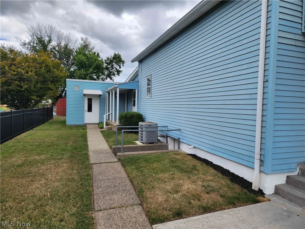 View of side yard featuring central air condition unit and a lawn