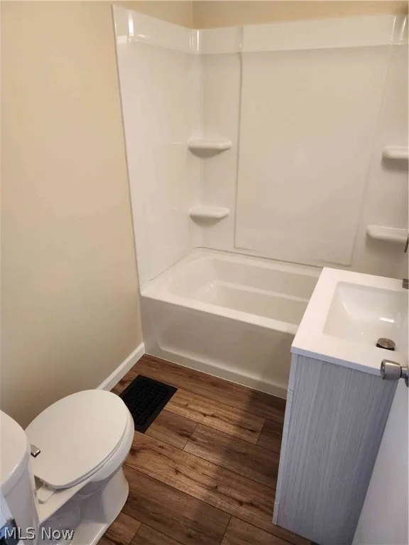 Full bathroom with wood-type flooring, shower / bath combination, toilet, and vanity