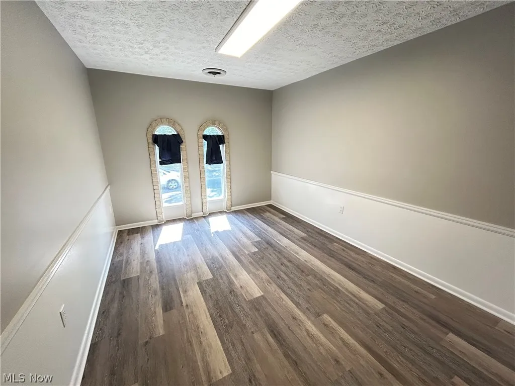 Unit A office featuring dark wood-style floors, windows, and a textured ceiling