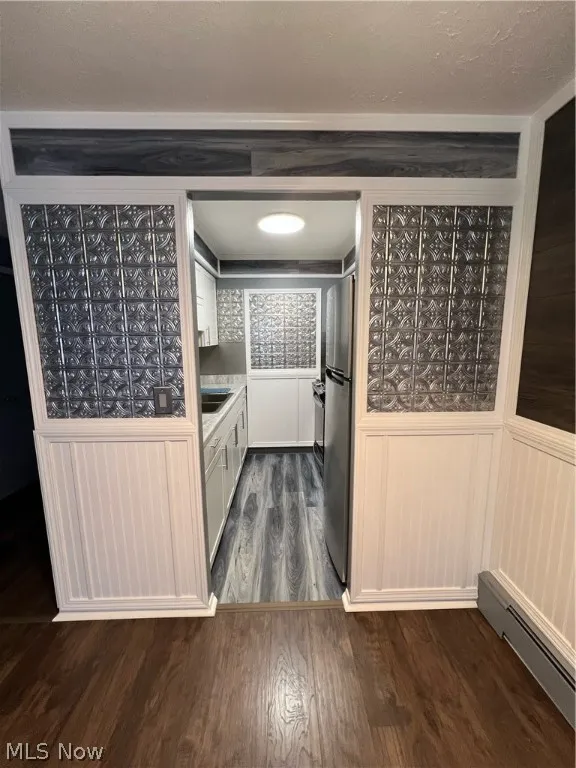 Kitchen with refrigerator, dark wood-type flooring, a baseboard radiator, and sink