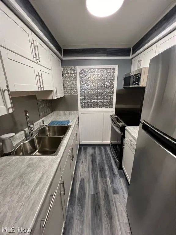 Kitchen with sink, dark wood-type flooring, fridge, and white cabinetry