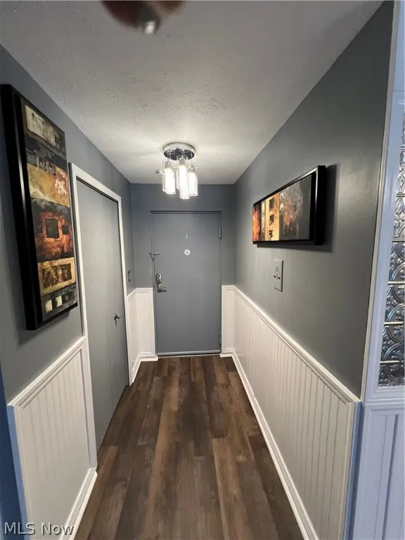 Corridor with a textured ceiling and wood-type flooring