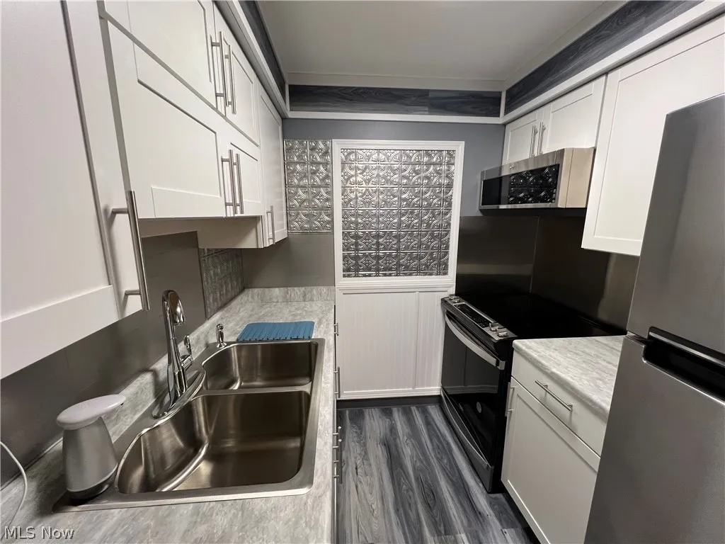 Kitchen featuring white cabinets, dark hardwood / wood-style flooring, appliances with stainless steel finishes, and sink