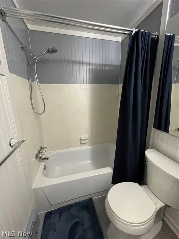 Bathroom featuring toilet and shower / tub combo with curtain