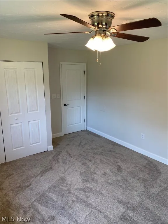 Unfurnished bedroom featuring a closet, carpet, and ceiling fan