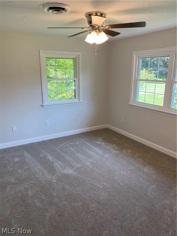 Unfurnished room with carpet flooring, ceiling fan, and plenty of natural light