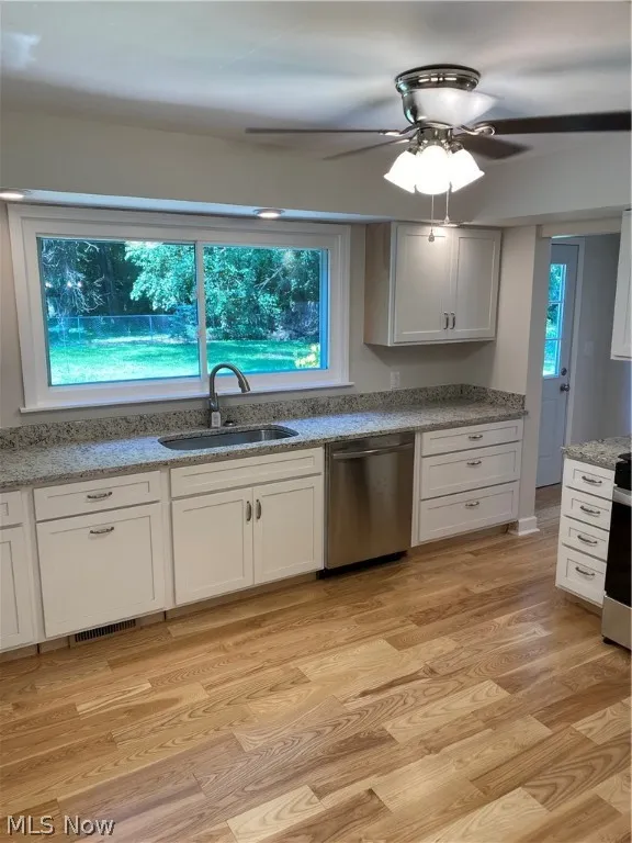 Kitchen featuring paneled dishwasher, sink, ceiling fan, and light hardwood / wood-style floors