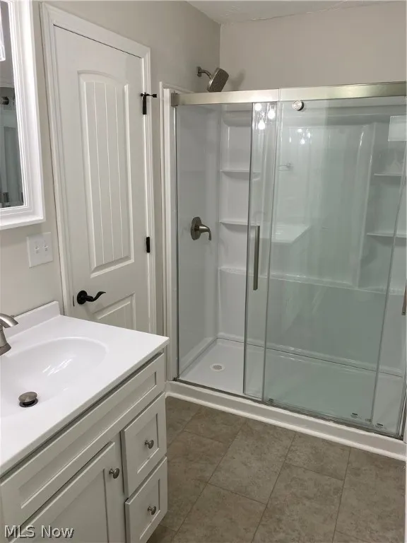 Bathroom featuring tile patterned flooring, vanity, and an enclosed shower