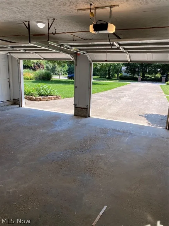 Garage featuring a garage door opener and a lawn