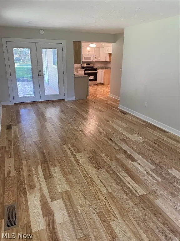 Unfurnished living room with french doors and light wood-type flooring